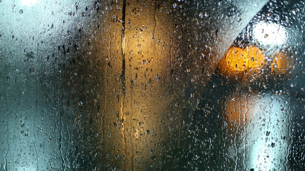 Gouttes de pluie perlent sur une vitre, symbolisant la purification intérieure et la douceur de la miséricorde divine en Islam